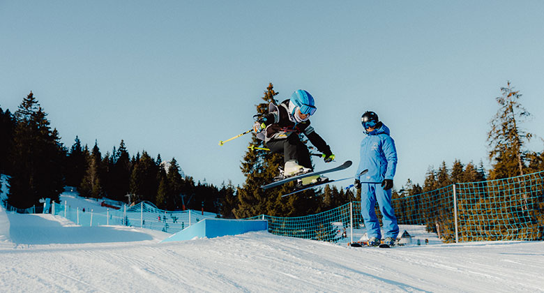 Skifahrer springt über einen Kicker im Funpark