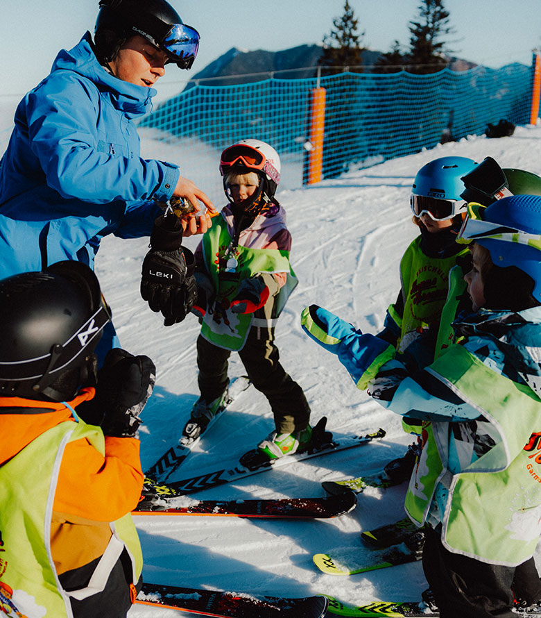 Skilehrer erklärt Kindern die Ausrüstung im Skikurs