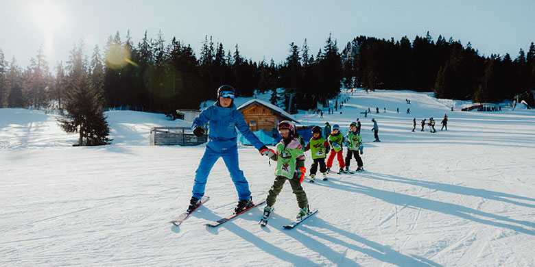Skilehrer führt eine Gruppe Kinder im Kinderskikurs